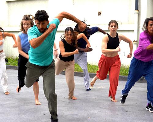 plusieurs danseurs habillés en vêtements du quotidien colorés dansent en même temps
